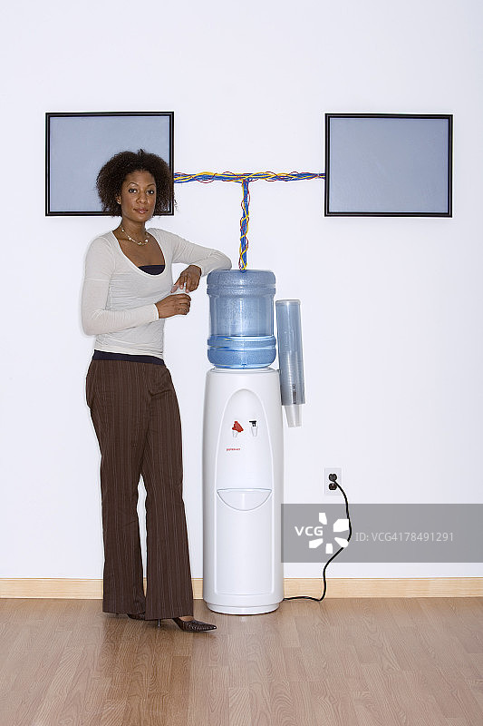 站在带液晶显示器的饮水机旁边的女商人图片素材