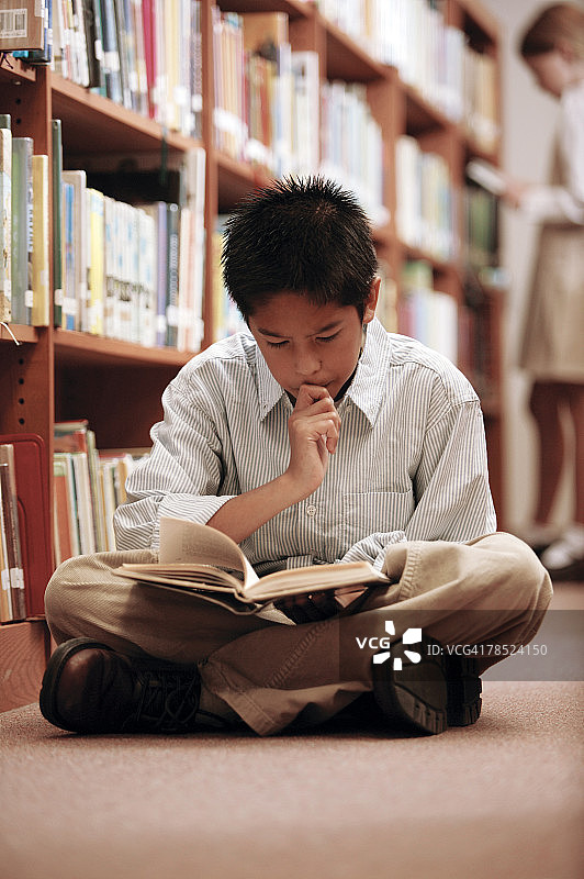 男孩在图书馆地板上读书图片素材