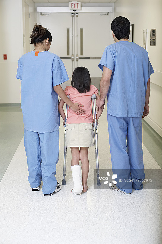 医疗专业人员帮助拄拐杖的女孩图片素材