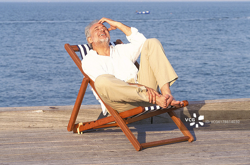 在码头躺椅上欢笑的男子图片素材