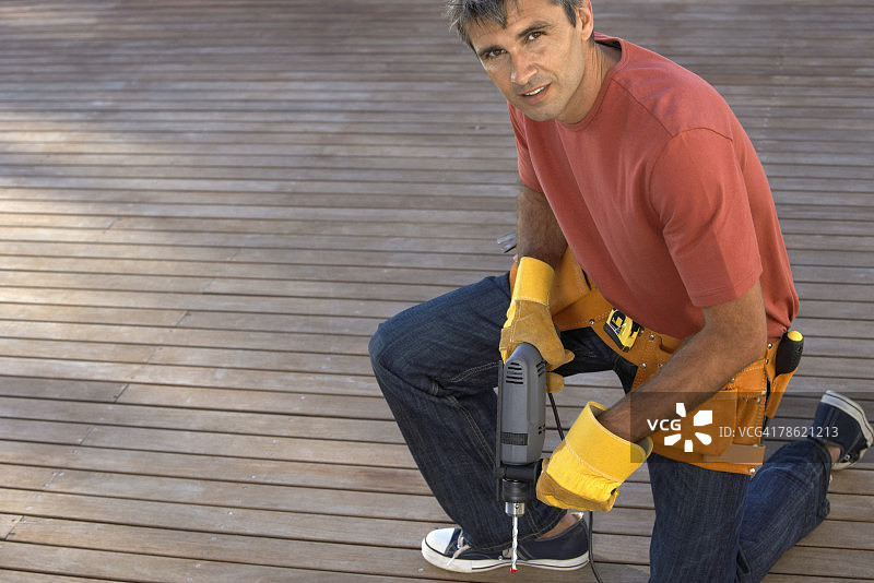 跪在甲板上拿着钻头的男人图片素材