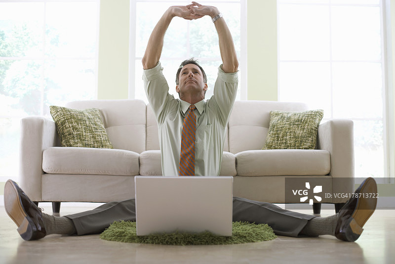 商人一边伸展身体一边使用笔记本电脑图片素材