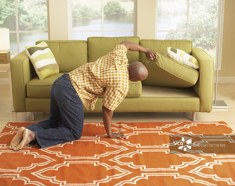 在沙发垫下寻找东西的男人图片素材