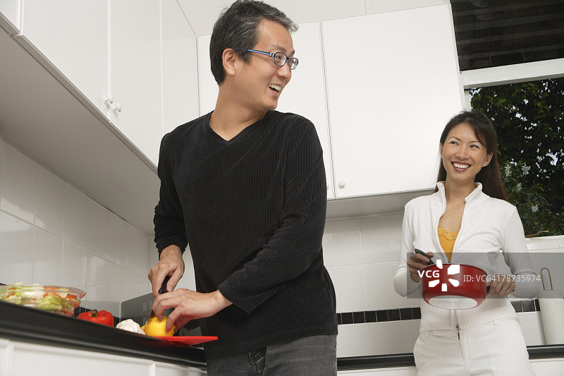 在厨房准备膳食、烹饪、彼此微笑的男女图片素材