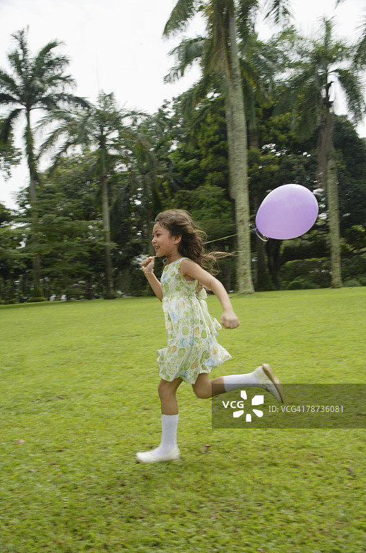 在公园奔跑的女孩，身后飞舞着紫色气球图片素材
