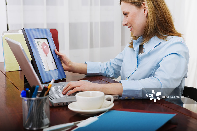 在办公桌上看相框照片的女商人图片素材