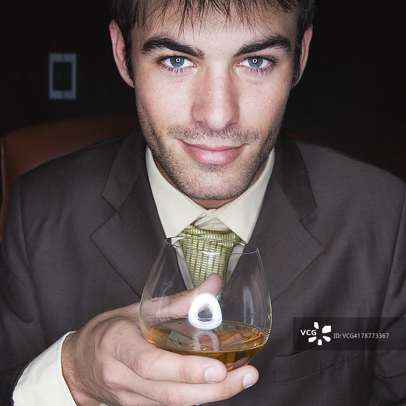 商人拿着白兰地酒杯图片素材