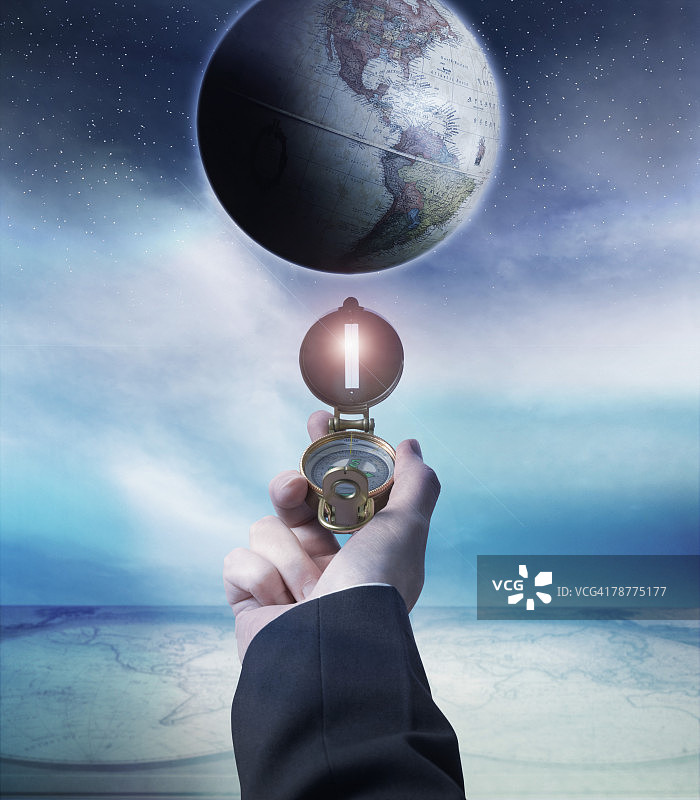 商人手持指南针靠近地球仪图片素材