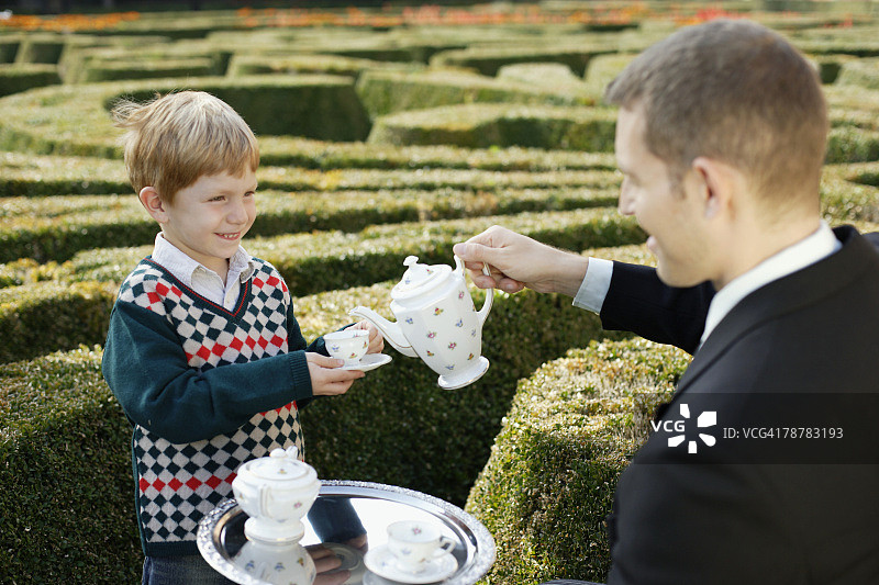 管家在庄园为男孩上茶图片素材
