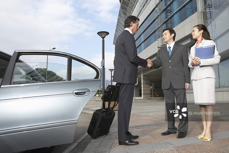 在办公楼外握手的商人图片素材