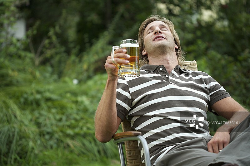 男人坐在草坪椅上喝啤酒图片素材