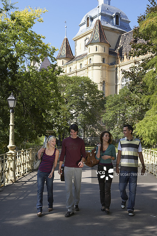 在桥上微笑行走的四个朋友图片素材