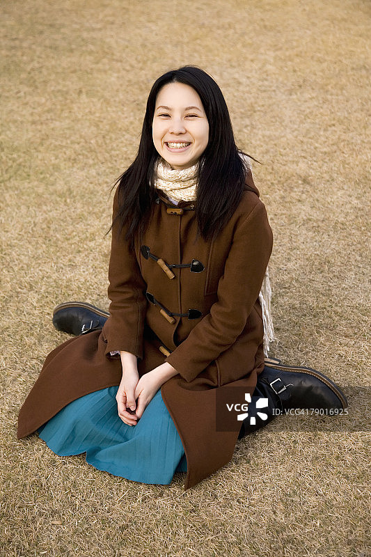 坐在草地上微笑的年轻女人图片素材