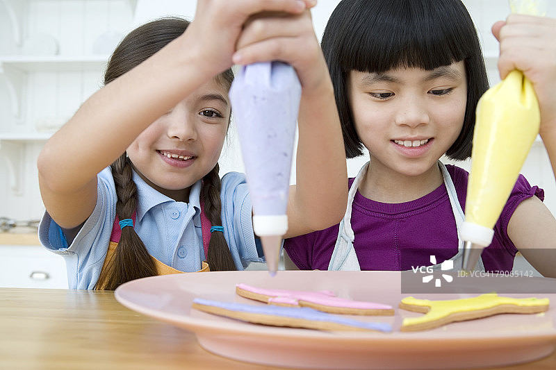 女孩给饼干上糖霜图片素材