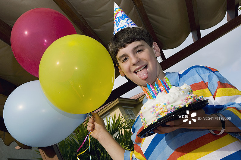 男孩手捧生日蛋糕和气球的肖像图片素材