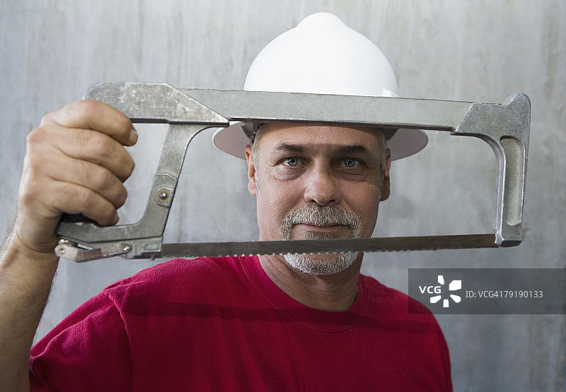 手持钢丝锯的年长男人肖像图片素材