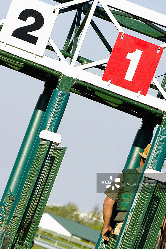 在赛马跑道起跑门上的两位赛马骑师图片素材