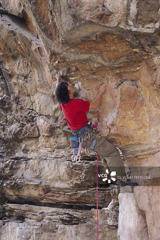 攀登岩壁的男性攀岩者背影图片素材