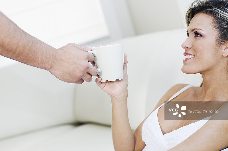男人手部特写，递给年轻女人茶杯图片素材