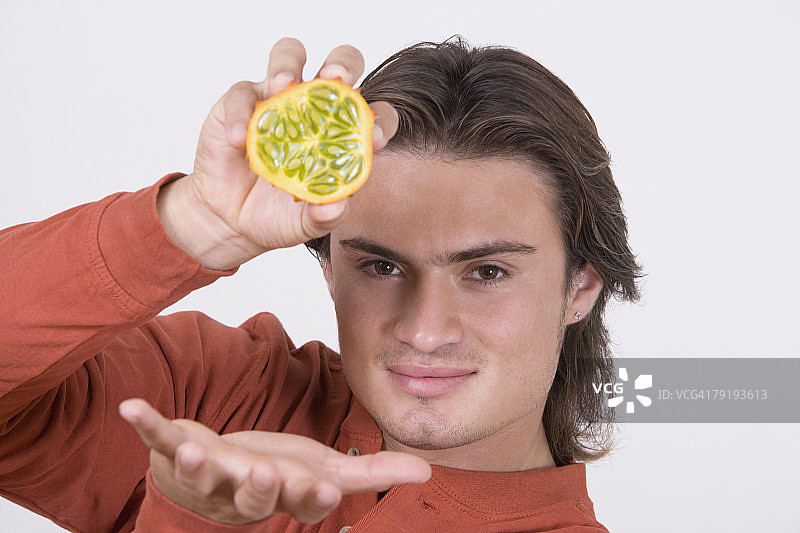 拿着半个卡瓦尼果的年轻男人肖像图片素材
