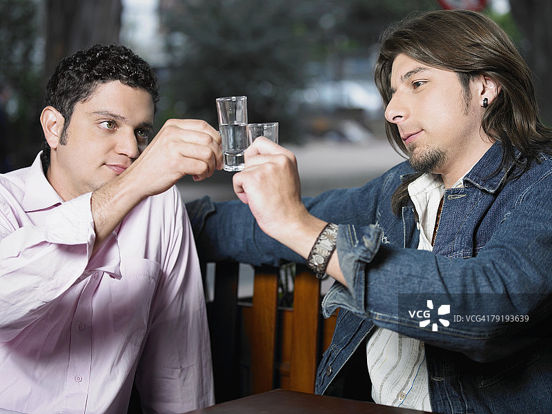 两个年轻男人用龙舌兰酒碰杯祝酒图片素材