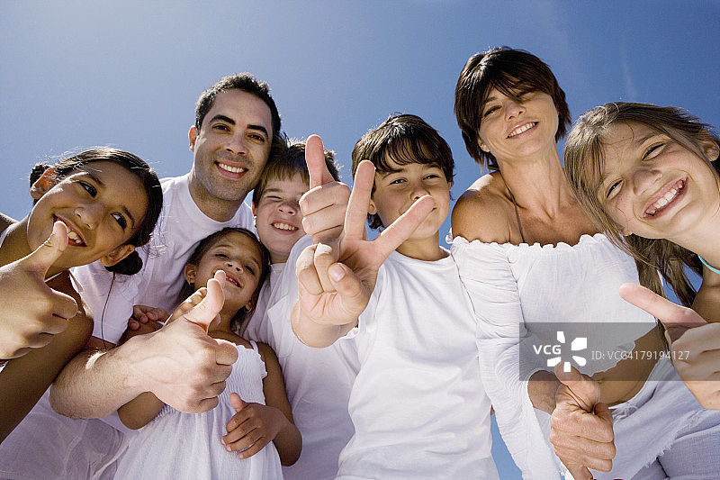与五个孩子一起做出和平与点赞手势的中年夫妇肖像图片素材