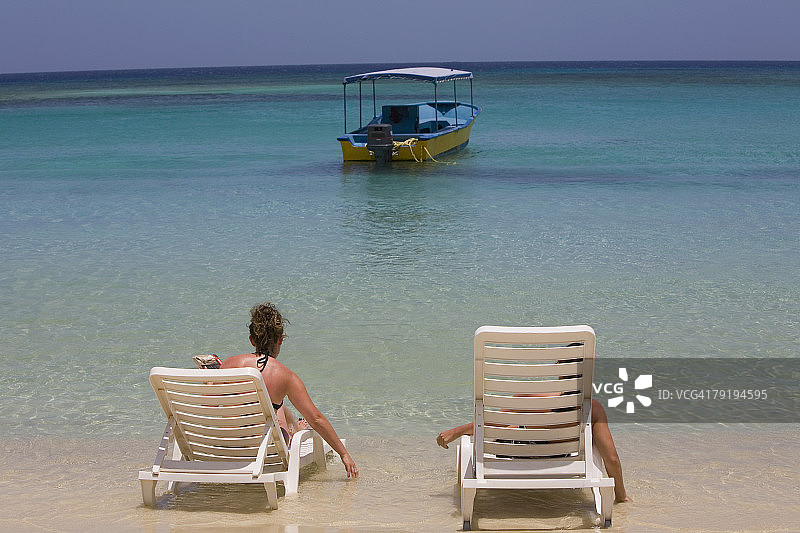 游客坐在洪都拉斯罗阿坦岛西湾海滩的沙滩椅上图片素材