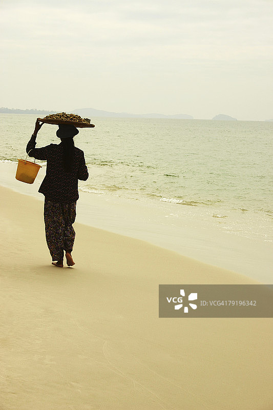女人在柬埔寨西哈努克城海滩上行走的背影图片素材