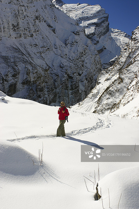 在尼泊尔喜马拉雅山脉安纳普尔纳山脉的雪景中行走的男徒步旅行者图片素材