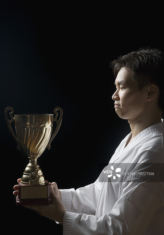 手持奖杯的年轻男子侧面轮廓图片素材