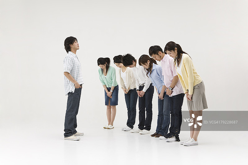 一群人向一个年轻人鞠躬图片素材