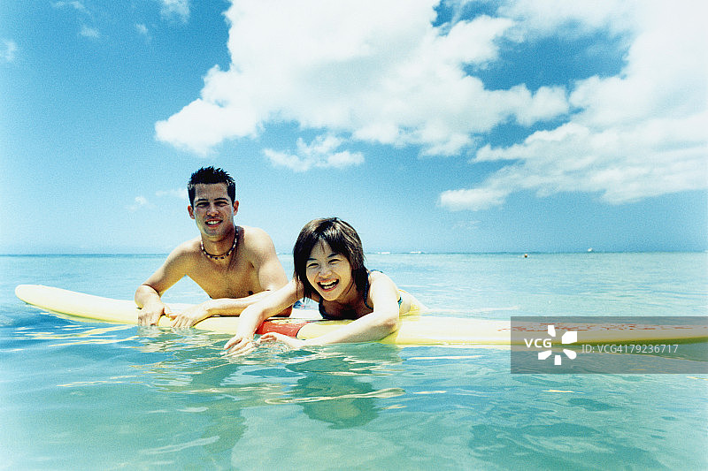 在水中玩冲浪板的年轻男女图片素材