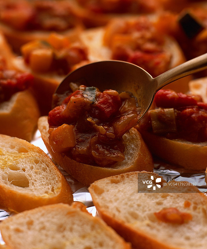 portioning mixed vegetables on sliced French loaf图片素材