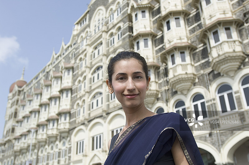 年轻女子在印度孟买泰姬陵皇宫酒店背景下的微笑肖像图片素材