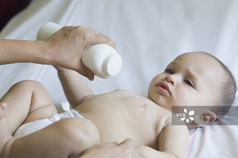 给婴儿胸前涂抹痱子粉特写图片素材