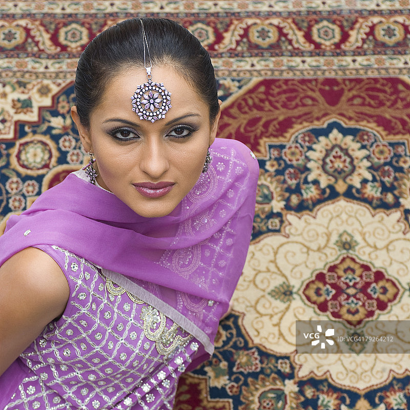 中年妇女穿着卡米兹坐在地毯上的肖像图片素材