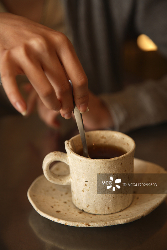 年轻女人用勺子搅拌茶的特写图片素材