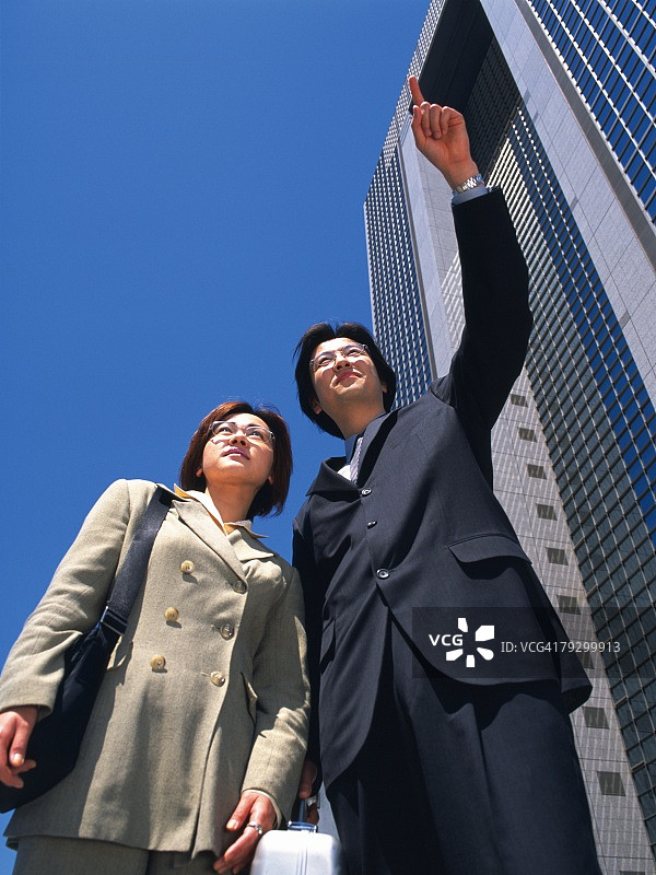 商务人士指向高层建筑旁的某物图片素材