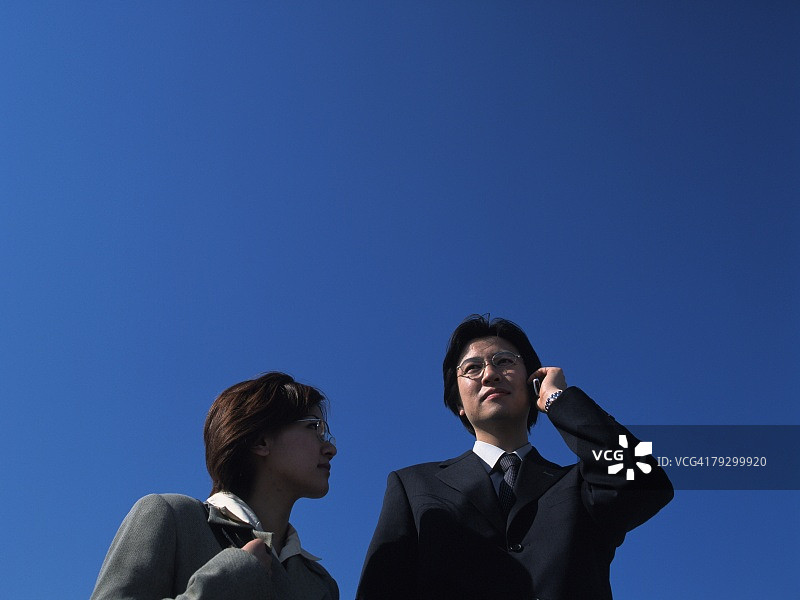 站在天空下的男、女商人肖像（仰视角度）图片素材