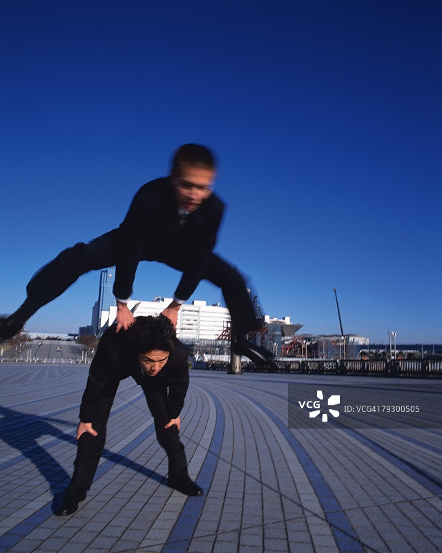 两名商人跳背，正面视角，长曝光图片素材