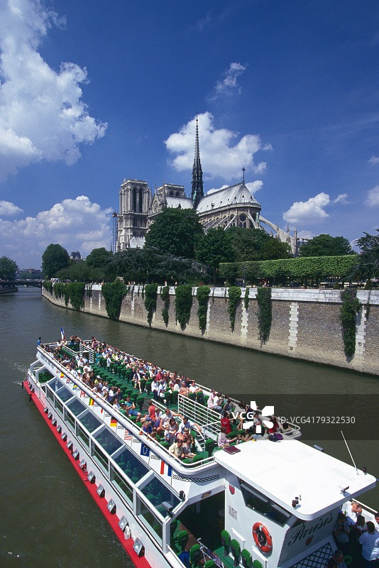 晴朗天气下塞纳河上的游船，背景是巴黎圣母院图片素材
