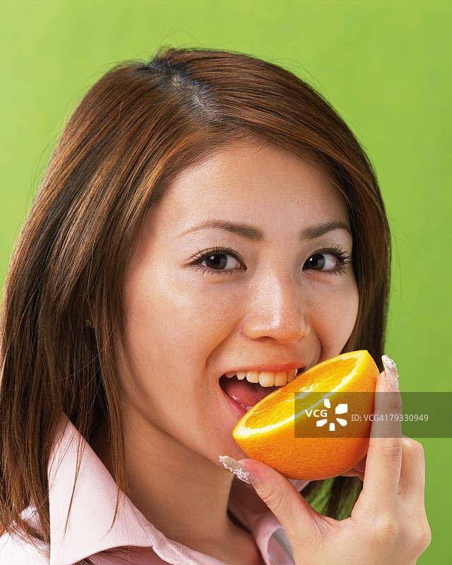 女子吃橘子，侧面看着镜头图片素材
