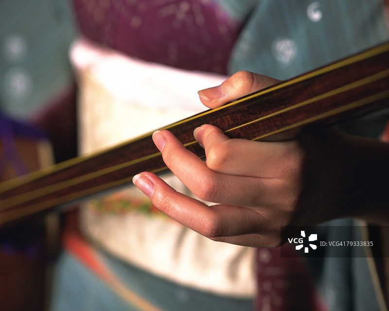 一位穿着和服的女子弹奏三味线，高角度特写镜头，差异对焦图片素材