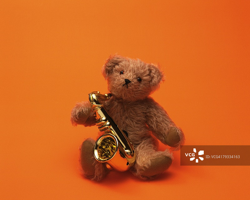 红色背景中抱着小萨克斯管的泰迪熊图片素材