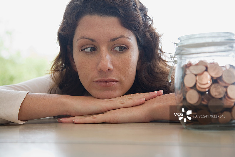 女子看着一罐便士图片素材