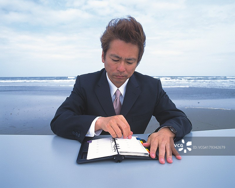 在海滩查看日程本的商务男士图片图片素材