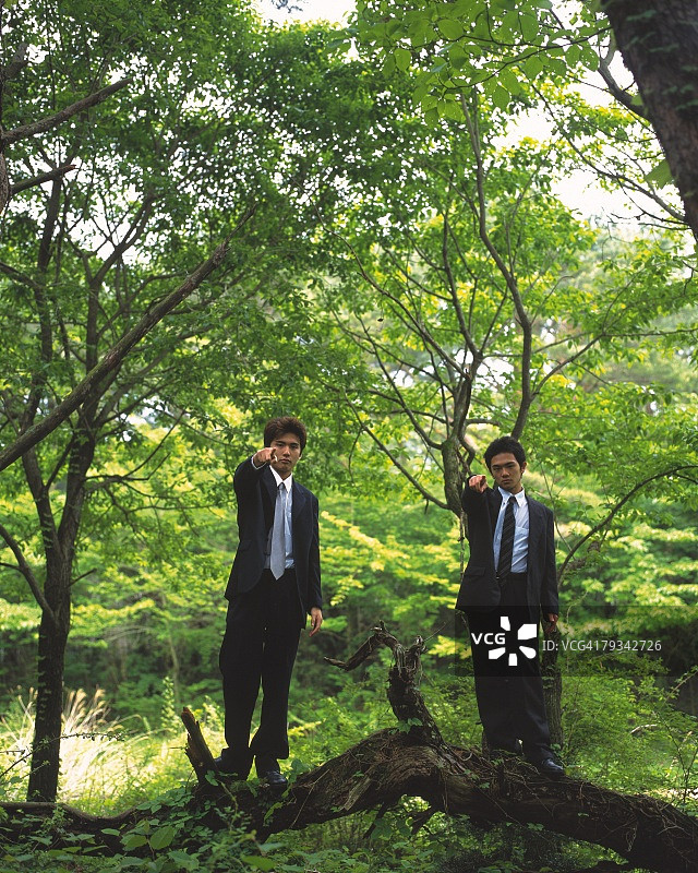站在森林中指向前方，看着镜头的两位商人（正面视角）图片素材