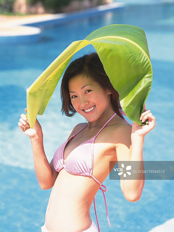 女子穿着比基尼，用大树叶遮阳图片素材