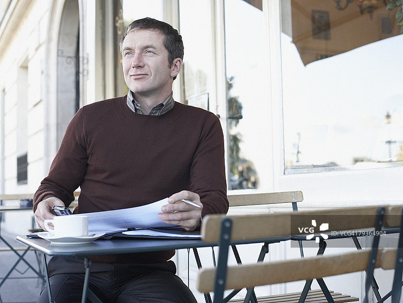 在餐厅外使用文件和手机的男人图片素材