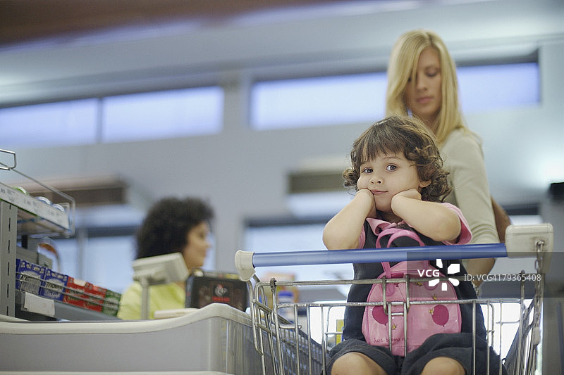 在杂货店与收银台的女人在一起的年轻女孩图片素材
